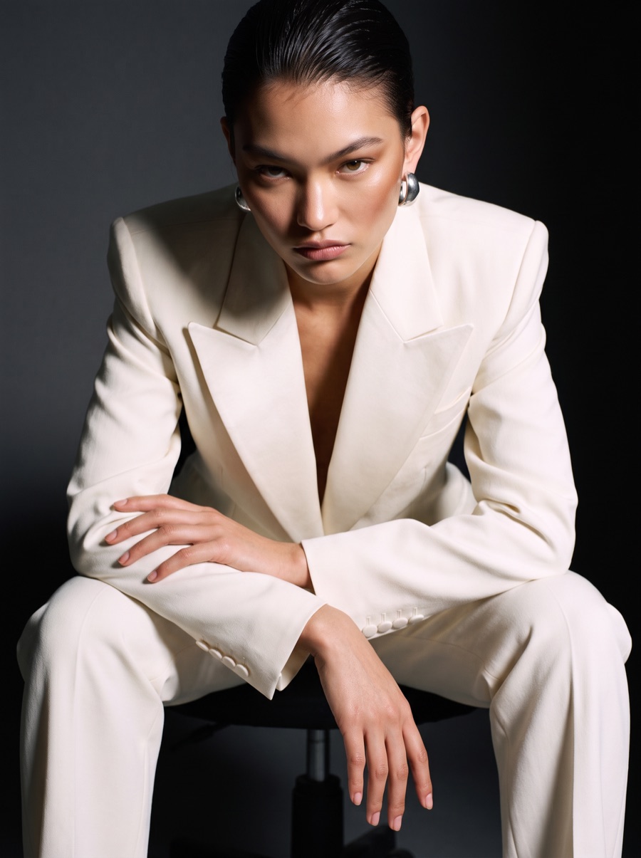 A founder in a cream suit leaning forward on an office chair